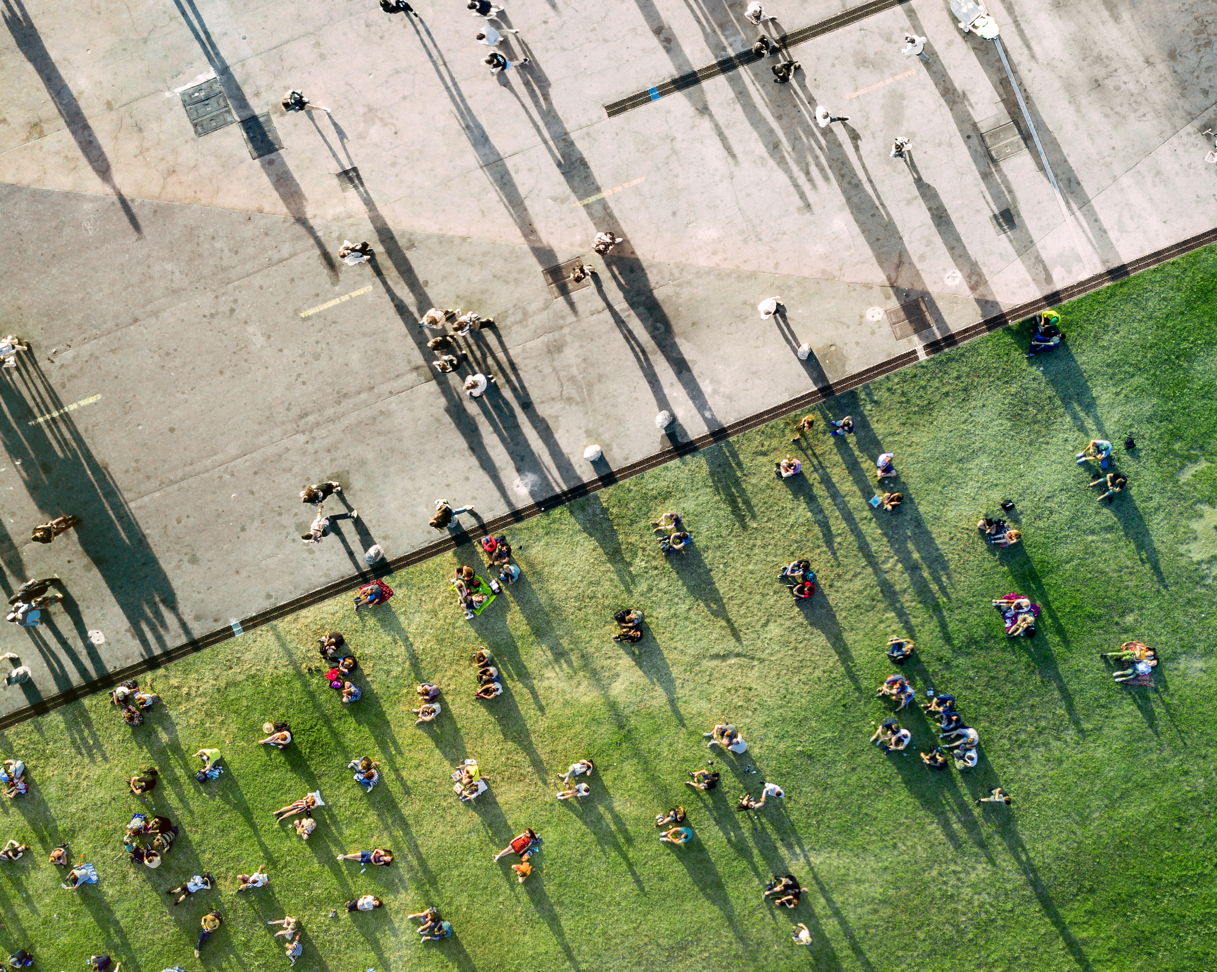 Luchtfoto van mensen die op een grasveld bij elkaar zitten en over straat lopen